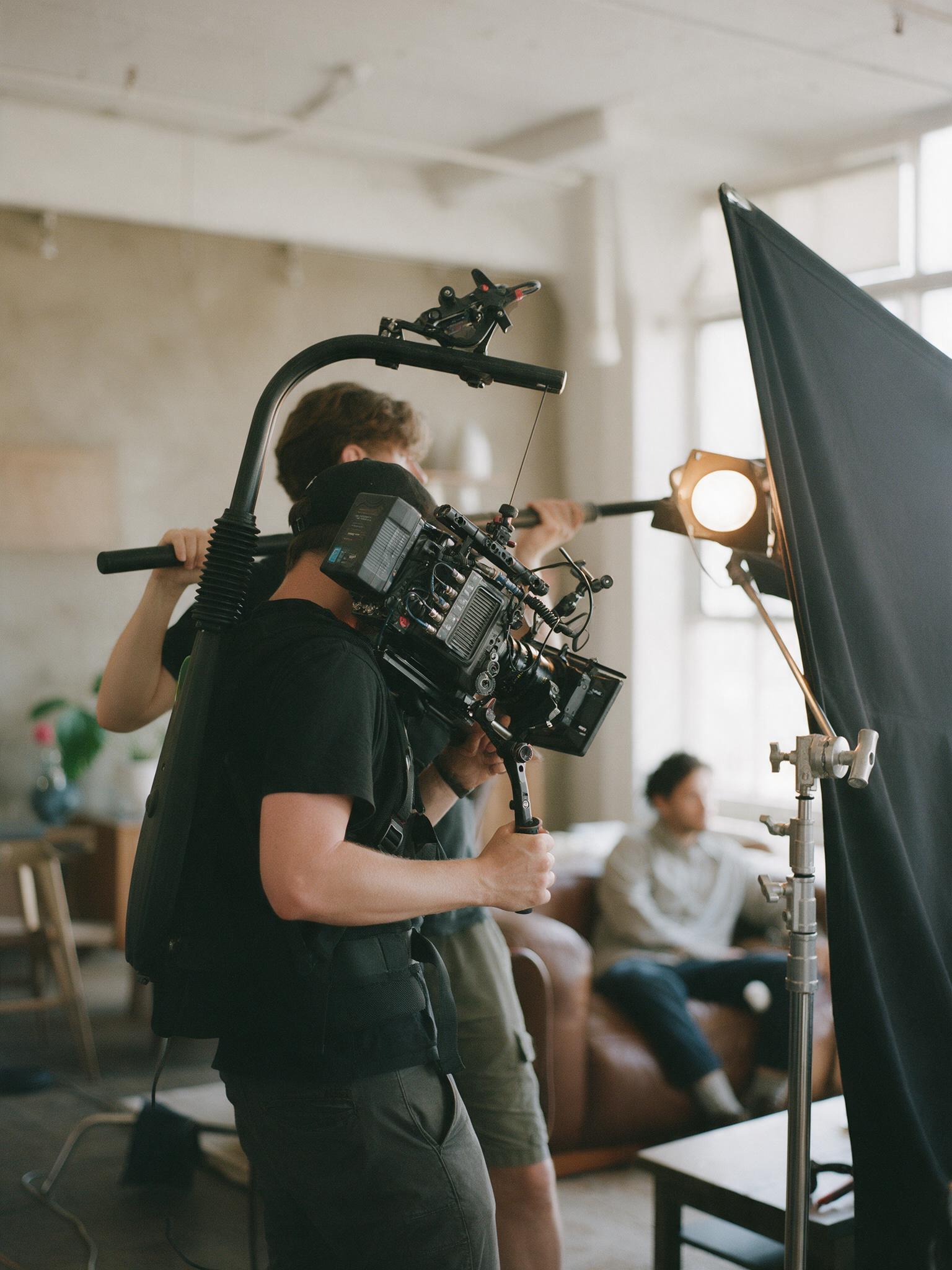 Camera operator with a cinema camera on a shoulder rig in a loft studio